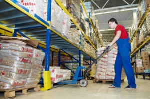 Image of a worker in a storage area pushing goods on a pallet truck